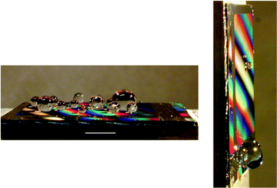 Collection of polydisperse water drops on a textured surface (the bar indicates 5 mm). When tilting the surface by α
						= 90°, most of the drops roll off, but the ones of radius smaller than Rc remain stuck. The mobile drops stop upon reaching the non-textured zone (without colors), to which they can stick, indicating a much larger value of Rc in this zone.